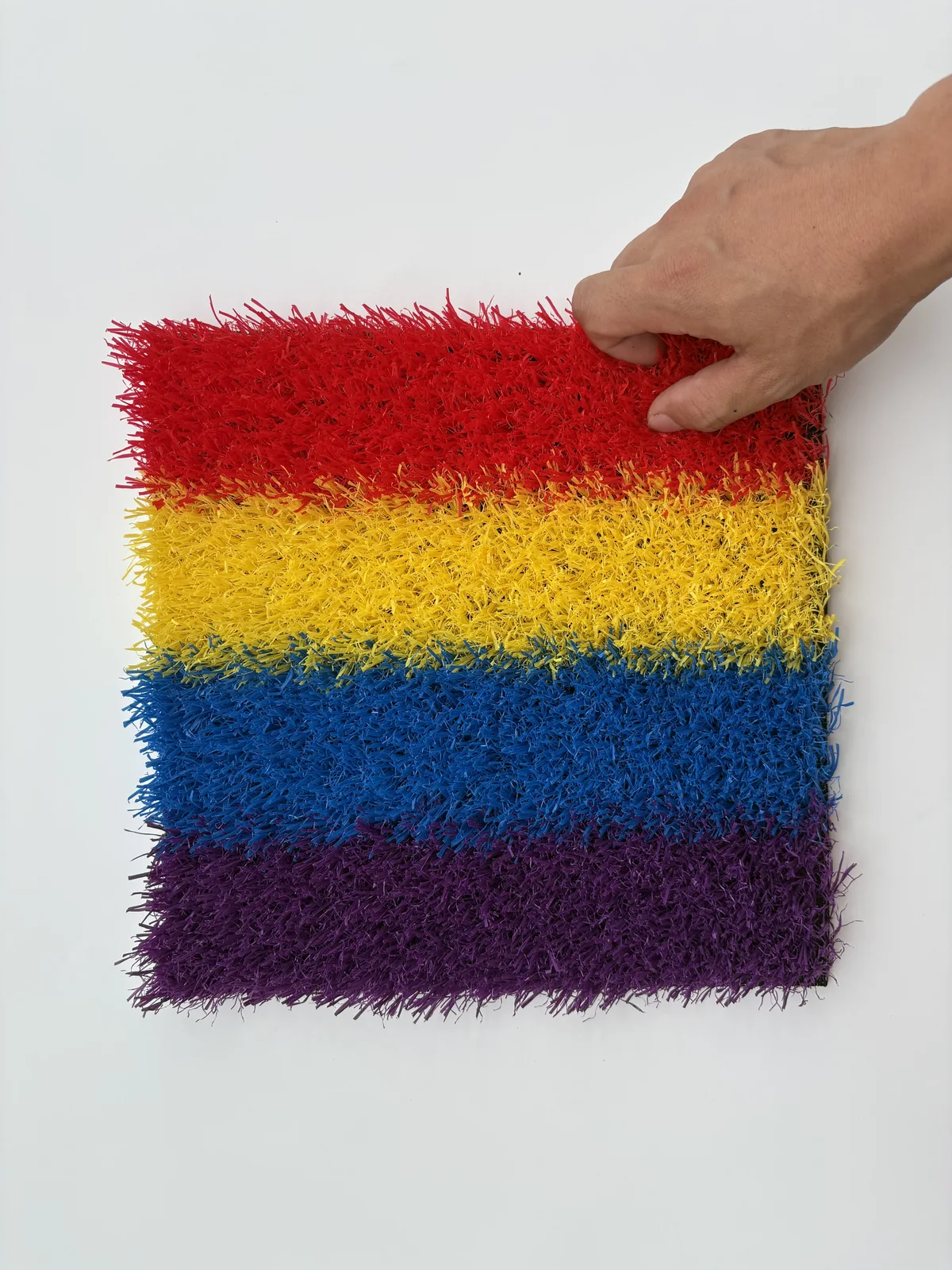 Colorful playground artificial grass hand scale and texture view
